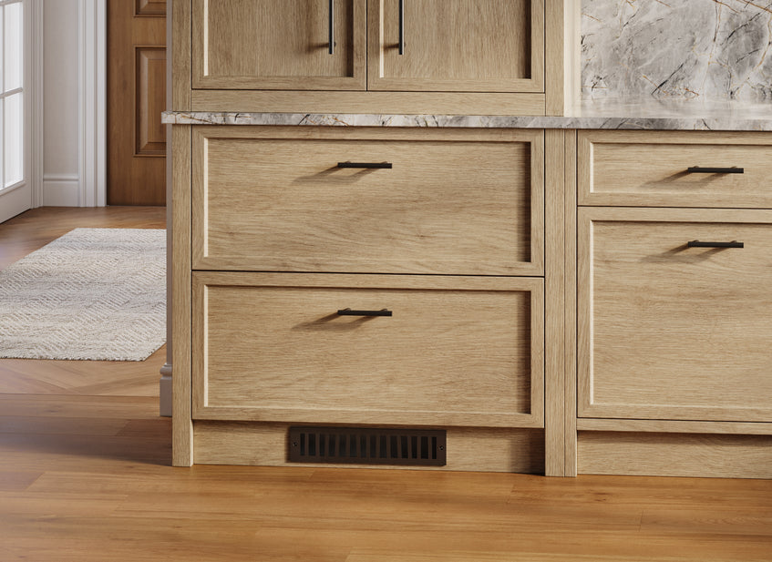 Wooden kitchen cabinets with dark hardware and a nature-inspired toe kick vent cover in oil rubbed bronze.  