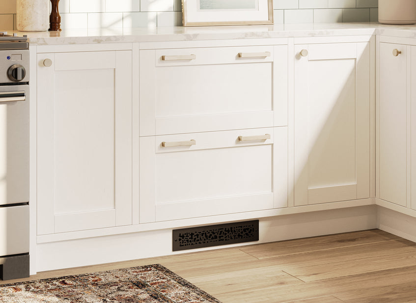 White kitchen cabinets with sleek brushed nickel hardware and a nature-inspired toe kick vent cover in oil rubbed bronze.